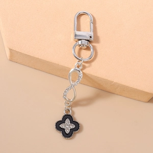 Macro shot of silver infinity charm and black enamel clover keychain with sparkling crystals