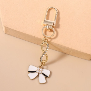 Detail of gold keychain featuring rhinestone infinity symbol and pearl bow pendant