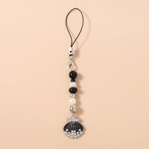 Detail view of a beaded phone strap with pearls and a black seashell pendant
