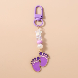 Detail of purple bead keychain with gold star pendants and footprints on warm background