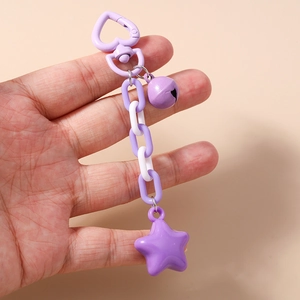 Close-up of a purple star pendant keychain with a heart clip and bell charm