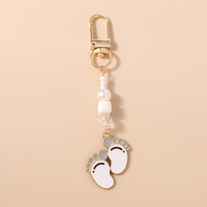 Detail of baby feet charm keychain with gold-plated paw prints and pearlescent beads