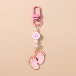 Detail of pink baby footprint charms and faceted beads on a golden keychain pendant