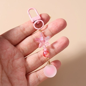 Close-up of pink beaded keychain with starfish charm and matte ball held in hand