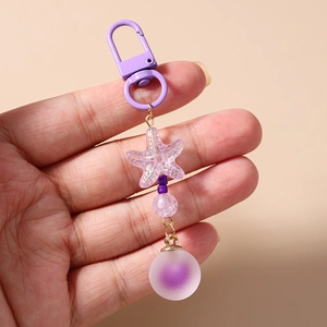 Detail of purple beaded keychain with starfish charm and matte sphere on gold lobster clasp