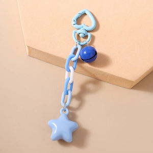 Detail view of blue star keychain with heart hook and bell on a geometric stand