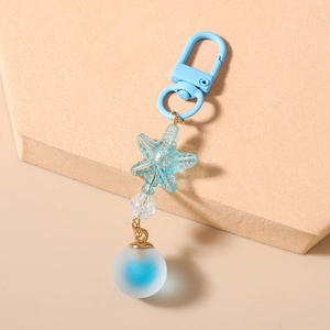 Detail of blue starfish keychain with frosted bead and carabiner on neutral background