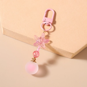 Detail view of pink starfish charm and frosted round bead keychain on beige steps