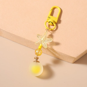 Detail of yellow starfish pendant and translucent matte ball on a metal keychain