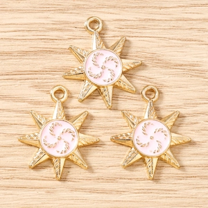 Detailed macro view of three gold star charms with pink enamel and spiral pattern