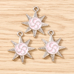 Detailed view of silver octagonal star charms with pink enamel and spiral metal pattern
