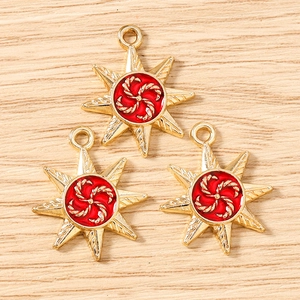 Detailed view of three gold eight-pointed star charms with red spiral centers on wood