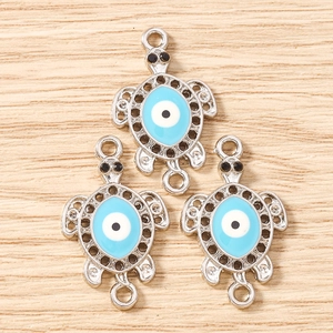 Detailed view of silver-plated sea turtle pendants with blue evil eye enamel and twin loops