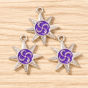 Detailed view of silver eight-pointed star pendants with purple enamel and spiral pattern