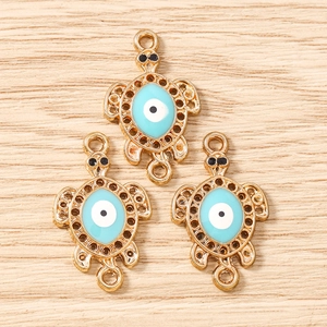 Macro detail of three golden alloy turtle pendants with blue enamel evil eye patterns