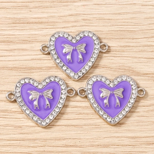 Detail von lila Emaille-Herzanhängern mit silberner Schleife und Strass für DIY-Schmuck