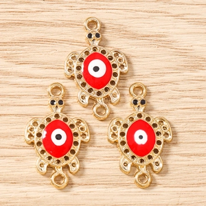 Macro detail of gold-plated turtle charms with red evil eye enamel for DIY jewelry