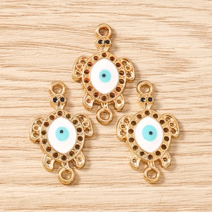 Detailed macro view of three gold turtle charms with evil eye pattern for DIY jewelry