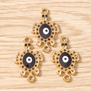 Detailed view of turtle-shaped connectors with evil eye enamel for DIY jewelry making