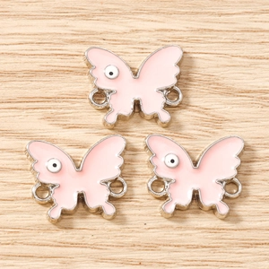 Close-up of pink butterfly alloy charms with eye patterns for DIY jewelry making