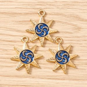 Detailed macro view of three gold star-shaped charms with blue enamel spiral for DIY jewelry