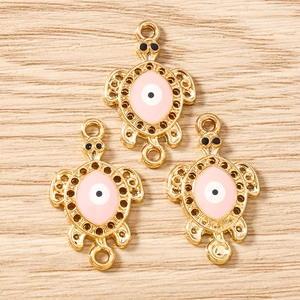 Macro detail of pink enamel turtle charms with evil eye pattern and double loops