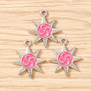 Macro detail of silver-tone octagonal star pendants with pink resin inlay on wood background