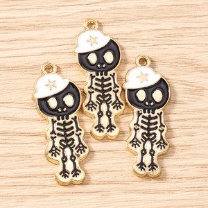 Vue macro de trois pendentifs tête de mort en émail noir et chapeau doré avec étoile