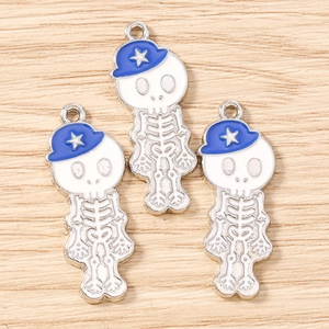 Détail de trois breloques crâne à chapeau bleu pour bijoux DIY sur fond de bois naturel