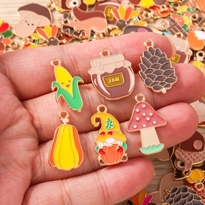 Herbstliche Emaille-Anhänger wie Kürbis und Pilz für DIY-Schmuck in der Hand