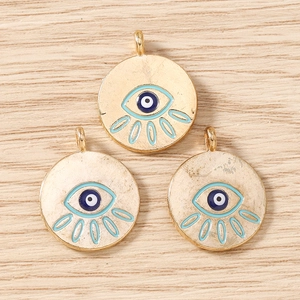Detail of three gold-plated evil eye charms with blue enamel inlay on wood surface