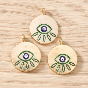 Detail of three gold alloy evil eye charms with green white and blue enamel for jewelry DIY