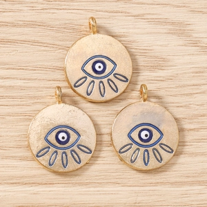 Macro view of gold-colored evil eye charms for jewelry making on wooden background