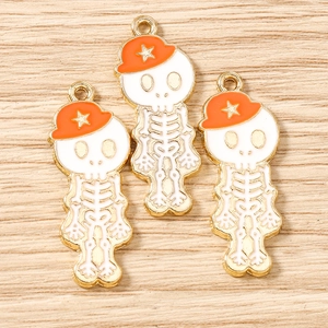 Vue détaillée de trois breloques crânes blancs avec chapeaux orange à étoile sur bois