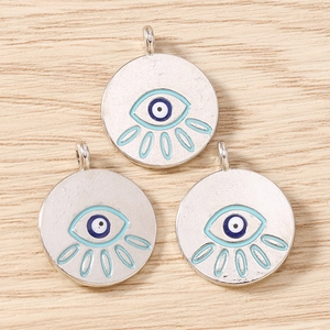 Macro view of silver plated evil eye charms with blue enamel on light wood background