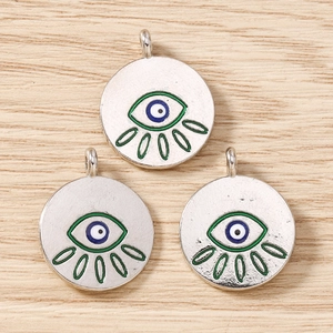 Macro detail of evil eye pendants with blue eye and green lashes for DIY jewelry making