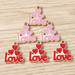 Enameled heart love charms in red and pink colors for DIY jewelry making on wood background