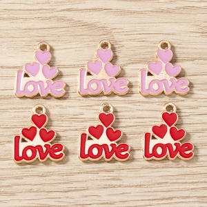 Detailed macro view of enamel LOVE pendants with heart charms for DIY jewelry on wood