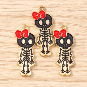 Detail view of skull charms with red bows and gold edges for DIY jewelry making projects