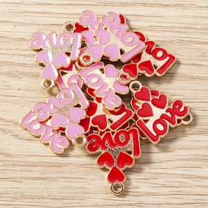 Macro detail of red and pink enamel heart pendants with LOVE engraving on wood surface