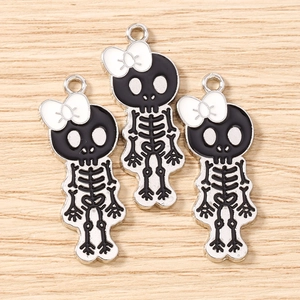 Close-up of alloy skull pendants with white bows for DIY jewelry making and necklaces
