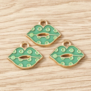 Macro detail of green enamel lip charms with gold alloy edges on light wood surface