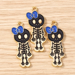 Detailed macro of dark cartoon skull charms with blue bow and gold-plated alloy finish