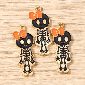 Three Halloween skull charms with orange bows in gold-plated alloy and enamel