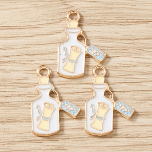 Détail macro de trois pendentifs émaillés en forme de bouteille pour bijoux DIY