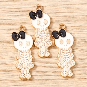 Three cute skeleton pendants with black bows on a natural wooden background for DIY jewelry