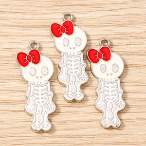 Three skull charms with red bows and white enamel finish for DIY jewelry crafting