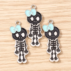Macro shot of three gothic-cute enamel skull pendants with mint blue bows on wood