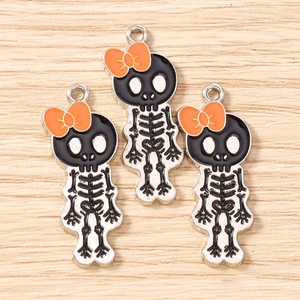 Three enamel skeleton girl charms with orange bows for DIY jewelry making and crafts