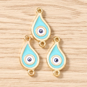 Drei blaue Emaille Evil Eye Anhänger mit Goldrand auf einem Holz Hintergrund